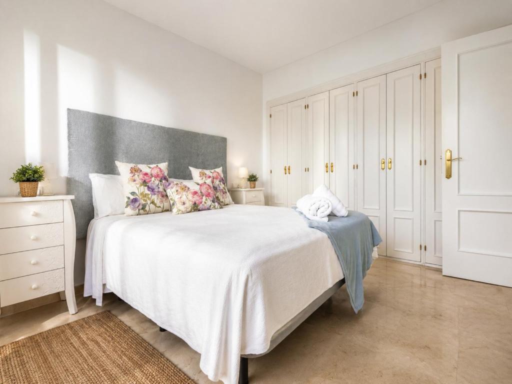 a white bedroom with a large white bed with pillows at Cristina Bungalow in Estepona