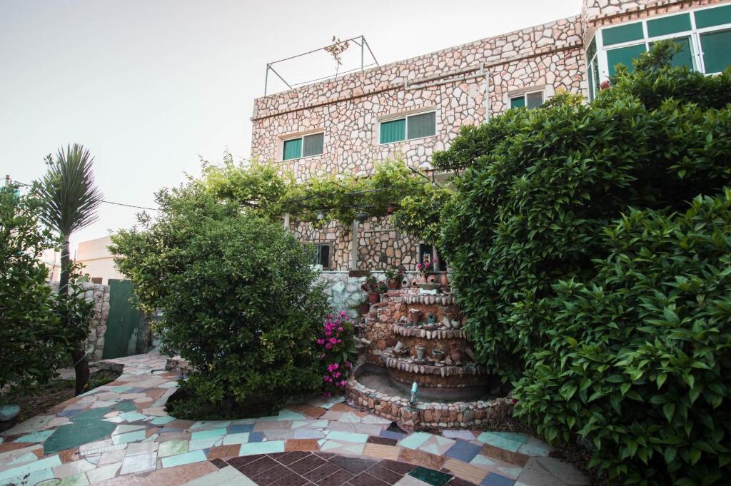 a brick building with a garden in front of it at Beit Al Baraka in Um Qeis