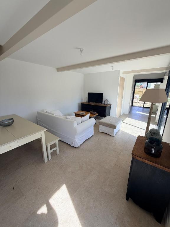 a white living room with a couch and a table at Grange 4 couchages in Mios