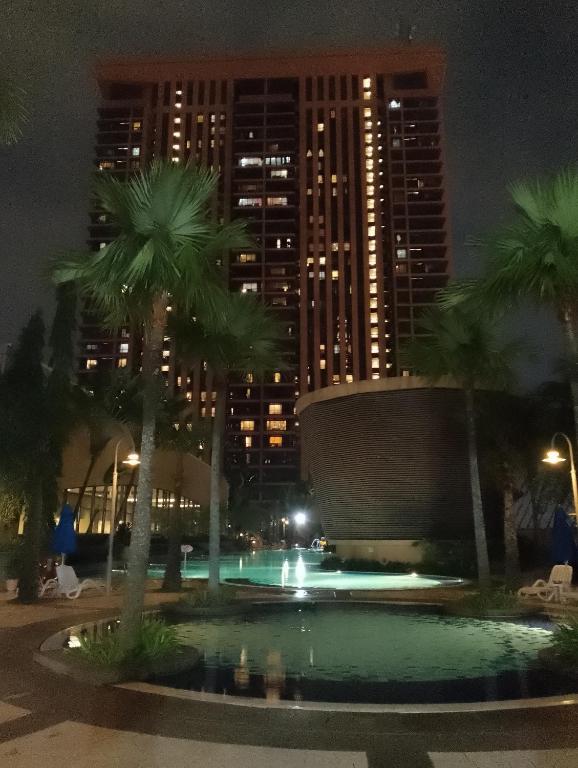 a pool with palm trees and buildings at night at Elevate suite Hotel time square kl in Kuala Lumpur