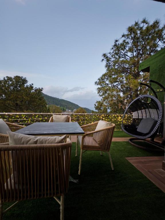 a patio with a table and chairs on the grass at The Crib, Murree Hills in Lower Topa