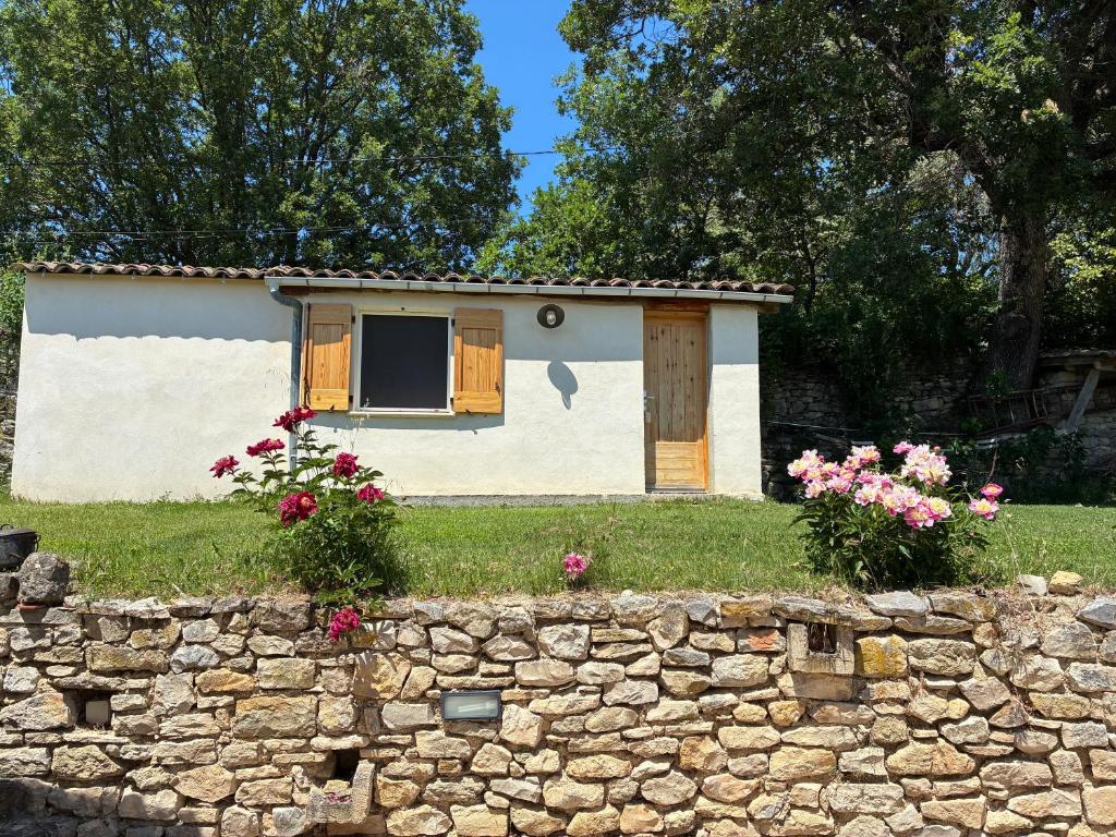 a small house with a stone wall and flowers at Le Cabanon de Pépé in Mane