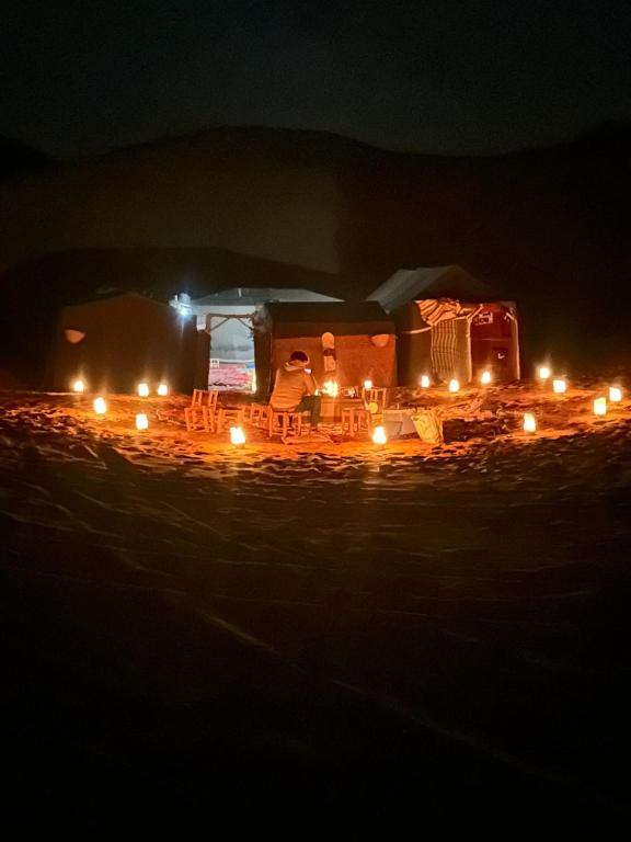 a camper at night with lights on at Moon Dunes camp in Adrouine
