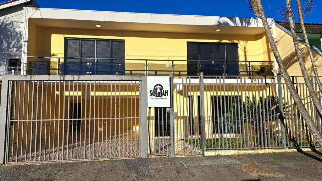 a yellow house with a fence in front of it at Sottam Hostel in Curitiba