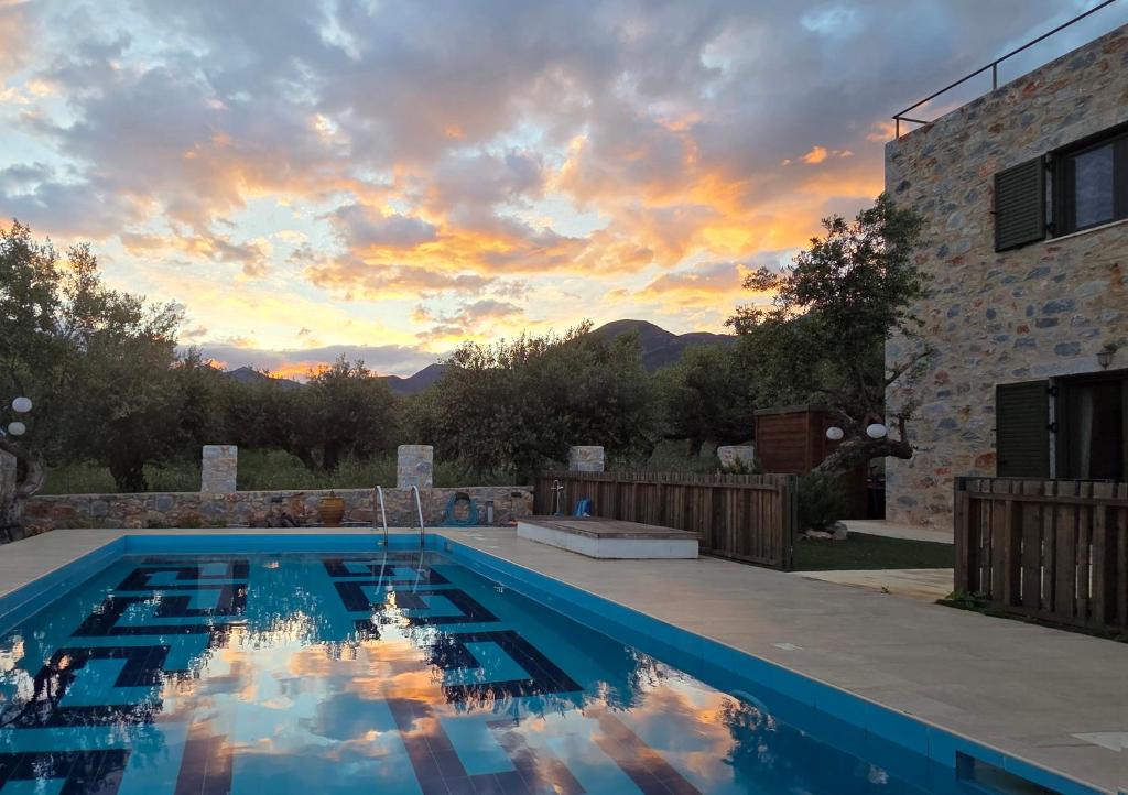 Ein Swimmingpool mit Sonnenuntergang im Hintergrund in der Unterkunft Spitiko Mas in Riglia