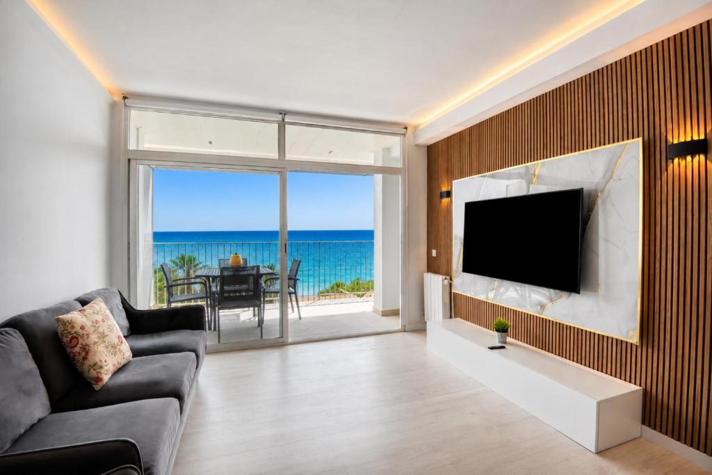 a living room with a couch and a tv and the ocean at Seafront apartment in Platja d'Aro with parking in Platja d'Aro