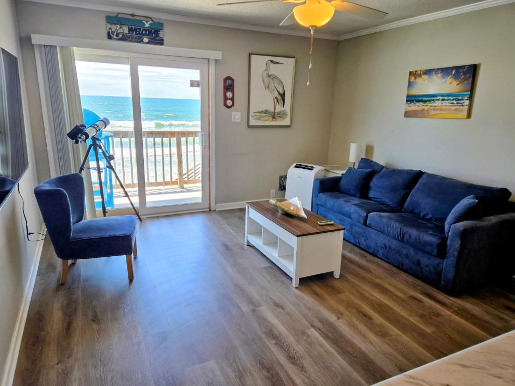 a living room with a blue couch and a table at Beachfront Condo 103 in North Topsail Beach