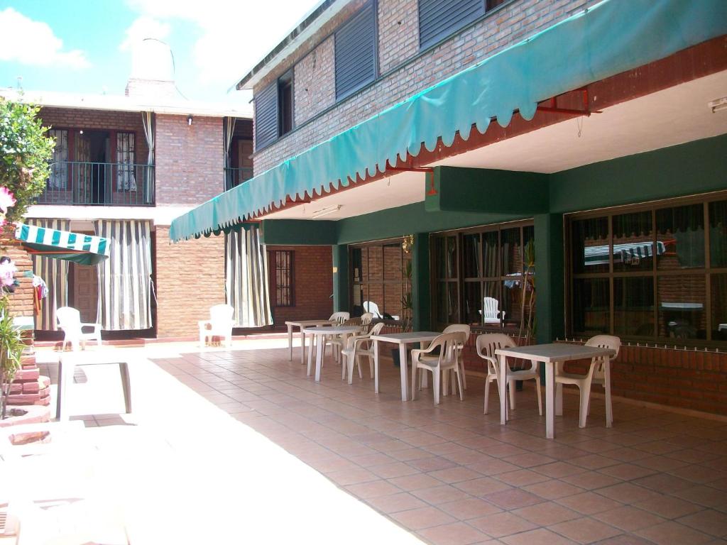 eine Terrasse mit Tischen und Stühlen auf einem Gebäude in der Unterkunft Hosteria Columbia in Mina Clavero