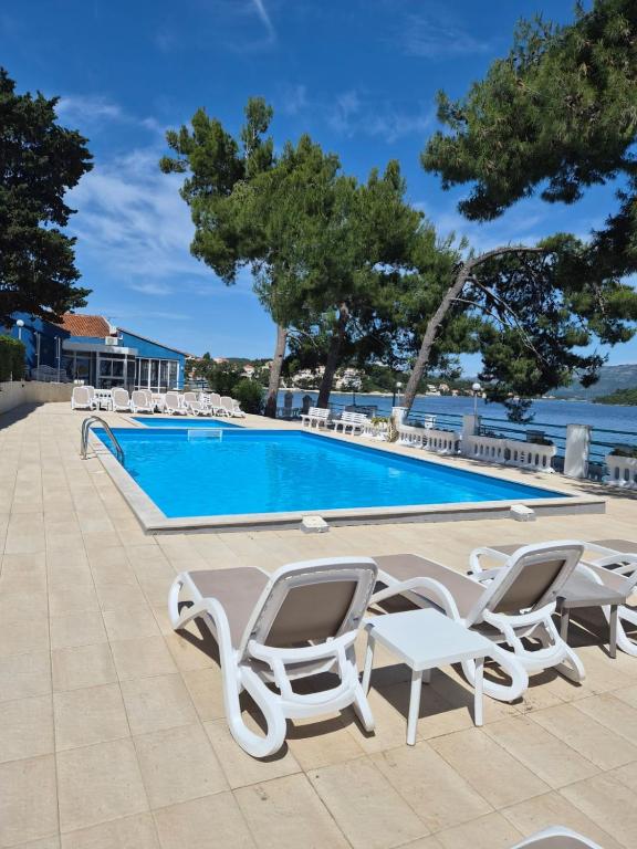 a swimming pool with chaise lounge chairs next to a swimming pool at Lumbarda Resort Apartments in Lumbarda