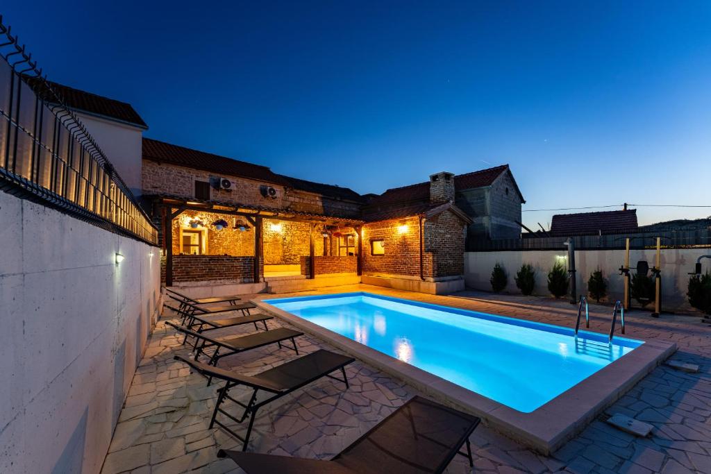 a swimming pool in the backyard of a house at night at Villa Dora with heated pool & fitness in Gradina