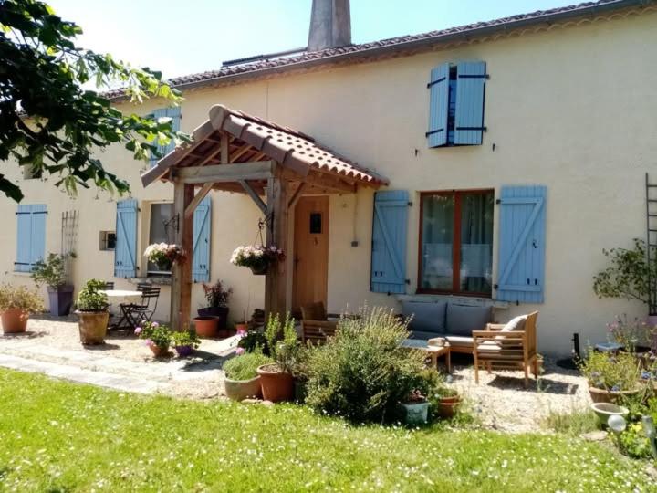 a house with blue shutters and a table and bench at Le Tilleuil in Combiers