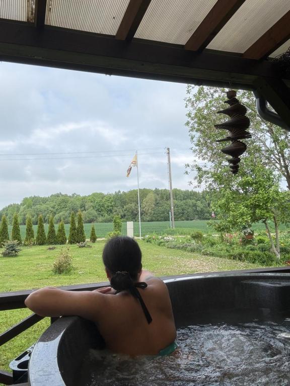 a woman is sitting in a hot tub at Medsukys - Namukai Dviem in Griniūnai