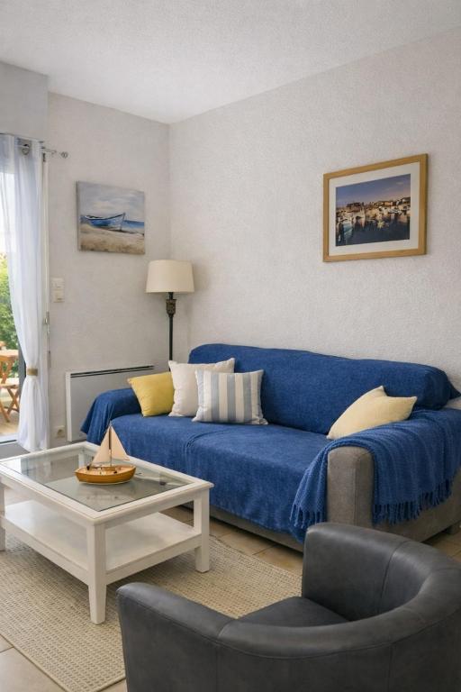 a living room with a blue couch and a table at Centre ville de Sarzeau, appartement au calme avec jardinet et parking privé in Sarzeau