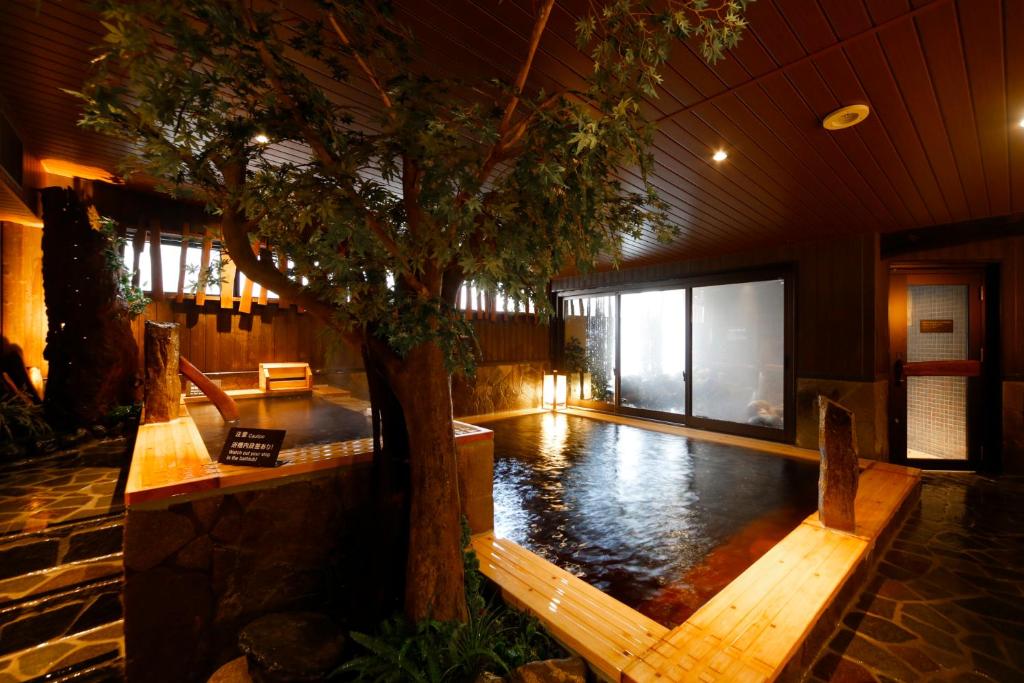 uma piscina com uma árvore no meio de um edifício em Dormy Inn Toyama Natural Hot Spring em Toyama