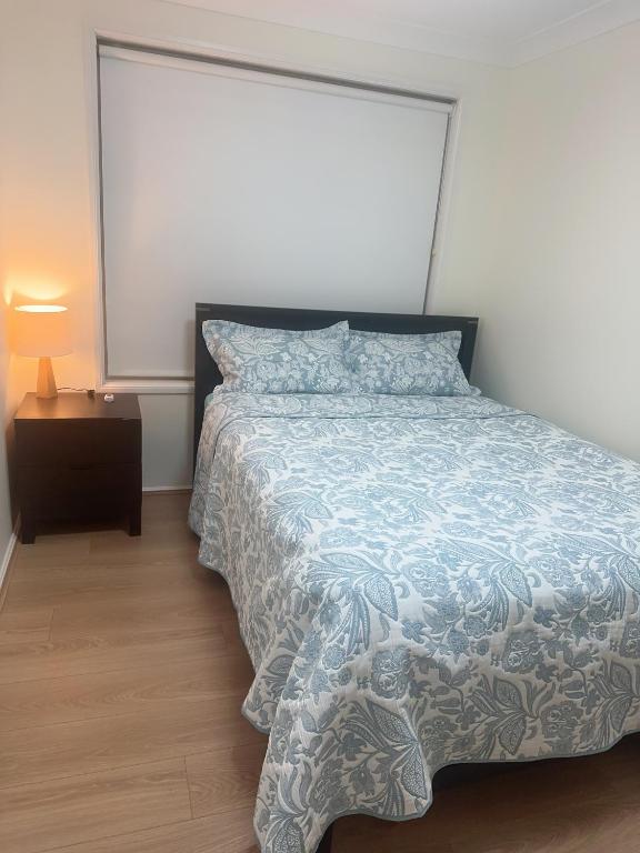 a bedroom with a bed with a blue and white comforter at Private Rm3 with Queen bed in Elderslie