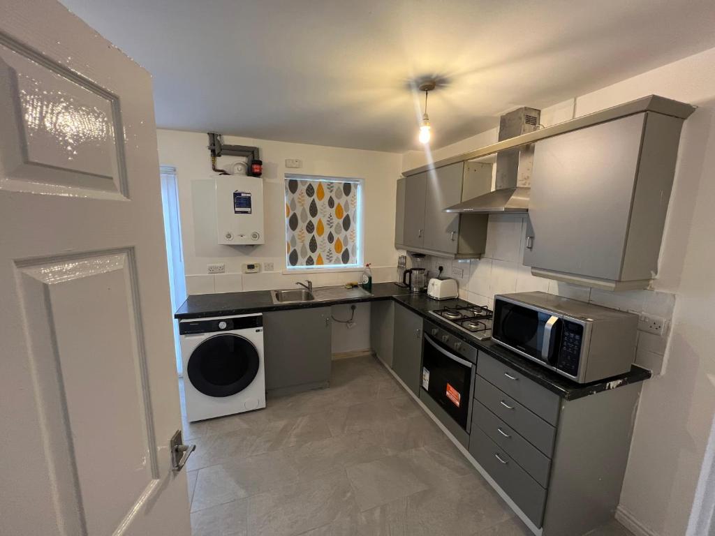 a kitchen with a stove and a microwave at Favour homes in Manchester