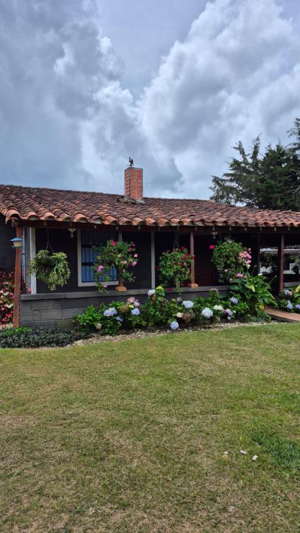 a house with flowers in front of a yard at Casa campestre in Guarne