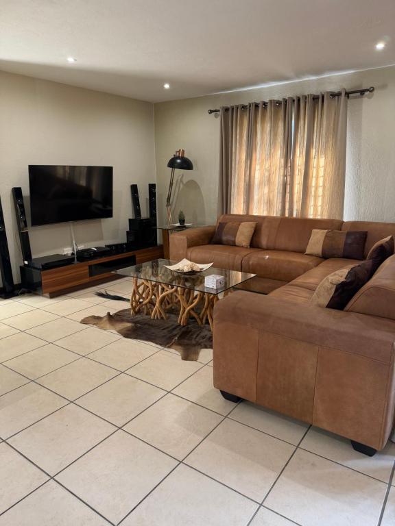 a living room with two brown couches and a flat screen tv at Caly Luxury Home in Nelspruit