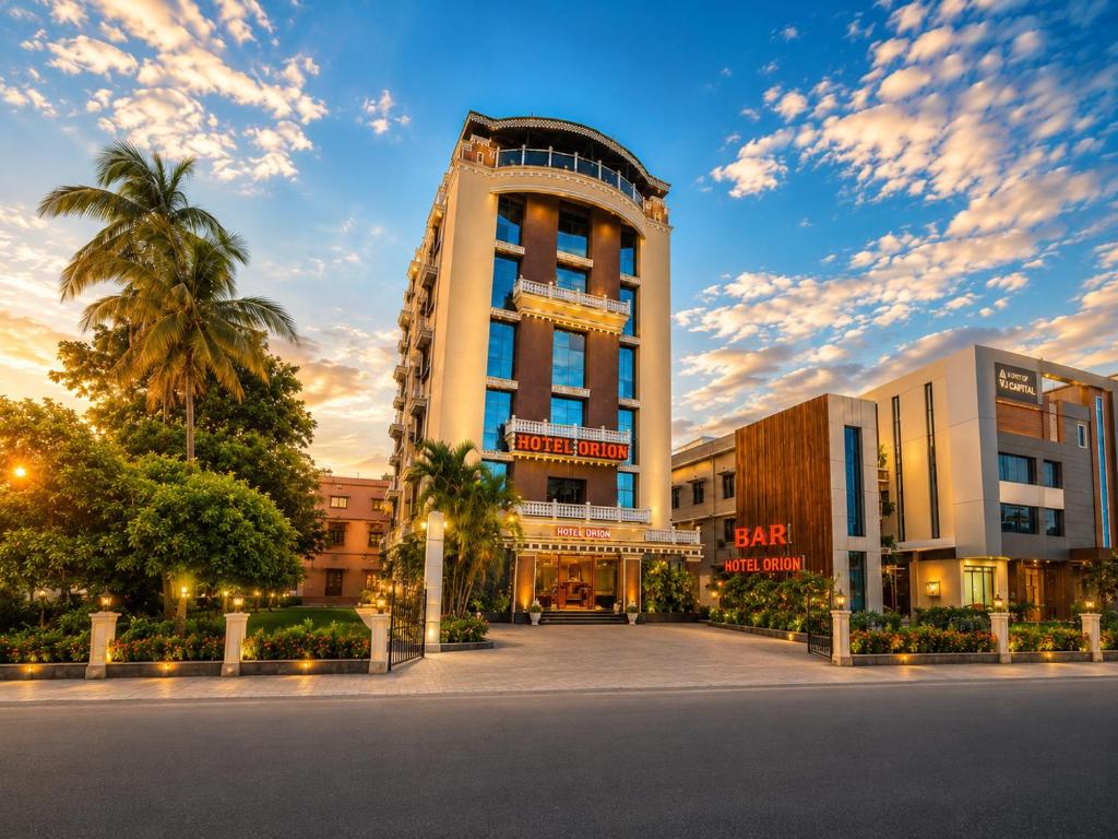 a building with a palm tree in front of it at Hotel Orion in Bhadrak