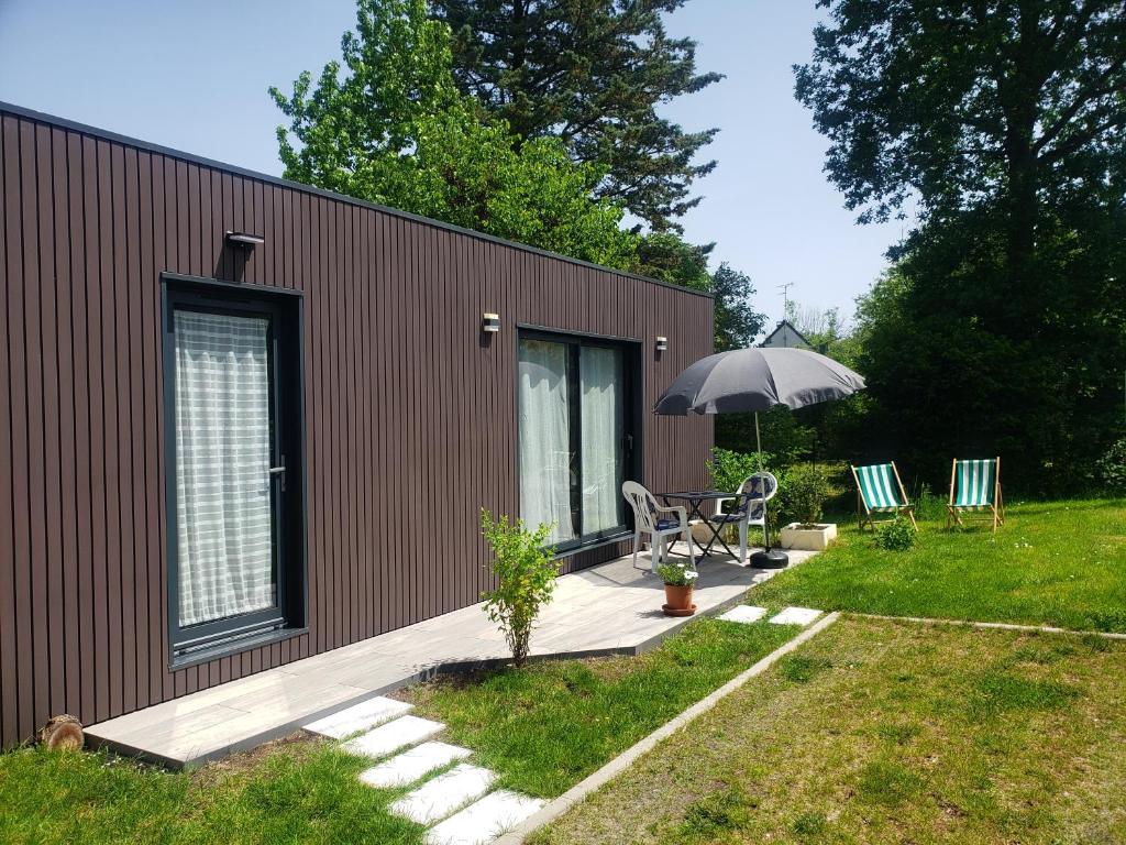 a small house with a patio and an umbrella at Campaville in Maurepas