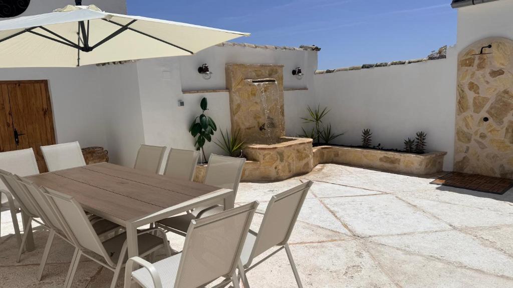 a wooden table and chairs with an umbrella on a patio at La Casa del Rey Alhamar in Arjona