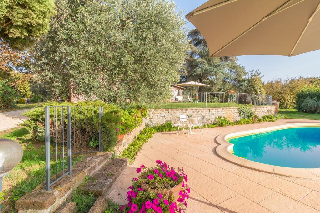 a patio with an umbrella and a swimming pool at Ai due Cedri Appartamento Nocciolo in Capranica