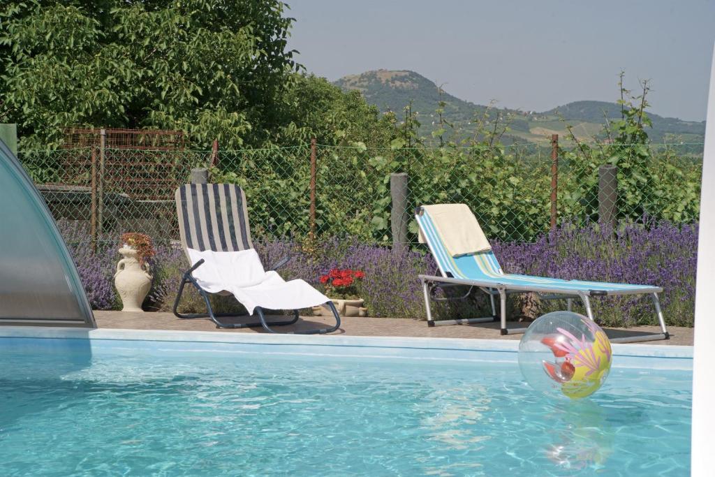a pool with two chairs and a ball in the water at Németh Apartman in Kisapáti