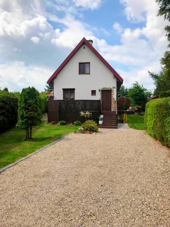a white house with a red roof on a gravel driveway at Dom Olena in Bogaczewo