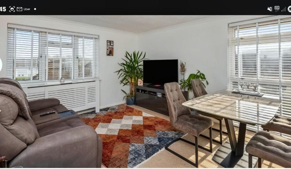 a living room with a table and a television at Cozy Flat in Steyning