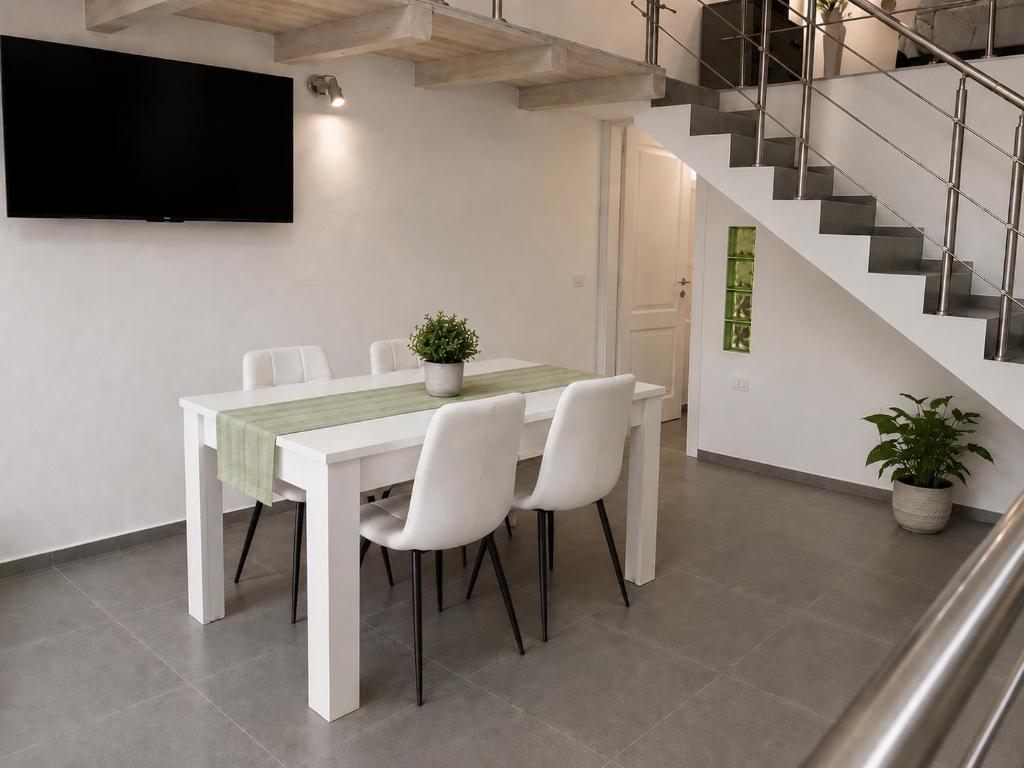 a dining room with a white table and white chairs at Urban charme loft in Dorgali