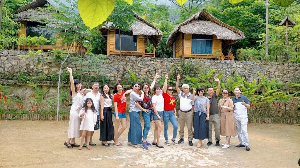 a group of people posing for a picture in front of a house at Homestay Hùng Phát Pù Luông in Làng Chiêu