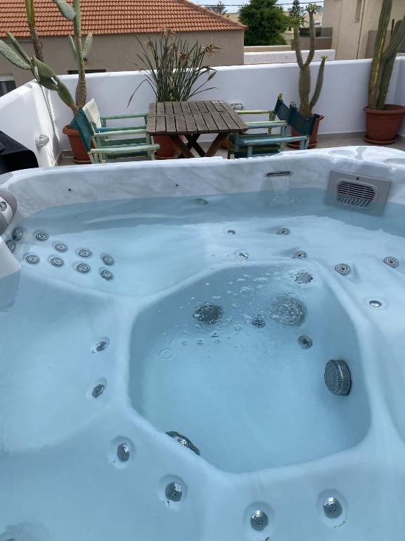 a jacuzzi tub on a patio with chairs at 2-Bed Blue & White Apartment with Jacuzzi, BBQ, Garden, near Beach in Platanias
