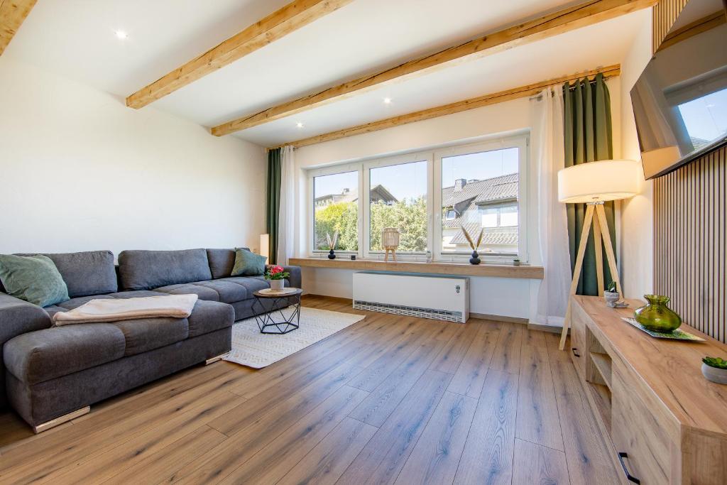 a living room with a couch and a large window at Ferienhaus Maarruhe in Schalkenmehren