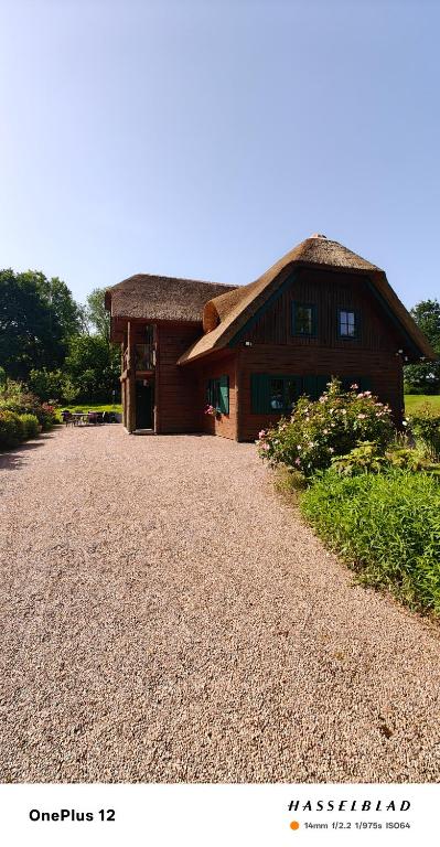 a building with a thatched roof and a gravel driveway at Chaumière d'Albâtre -Gîte-Détente nature et bien être in Ourville-en-Caux