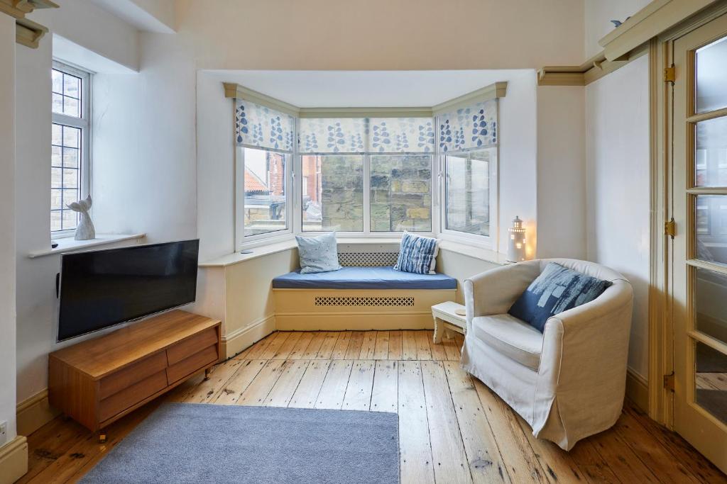 a living room with a tv and a chair and a window at Sandy Toes in Sandsend