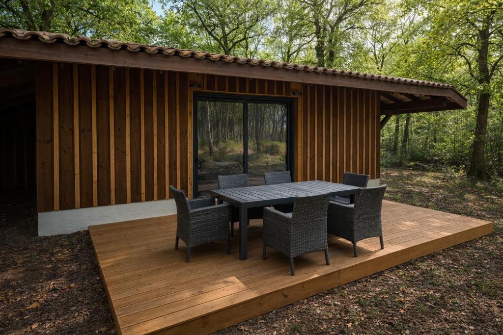 a table and chairs on a deck in front of a cabin at Les cabanes in Noaillan