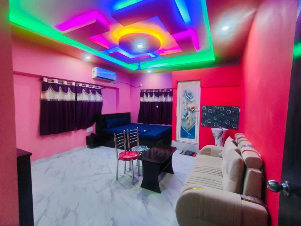 a living room with pink and green lights on the ceiling at Hotel Happy House in kolkata