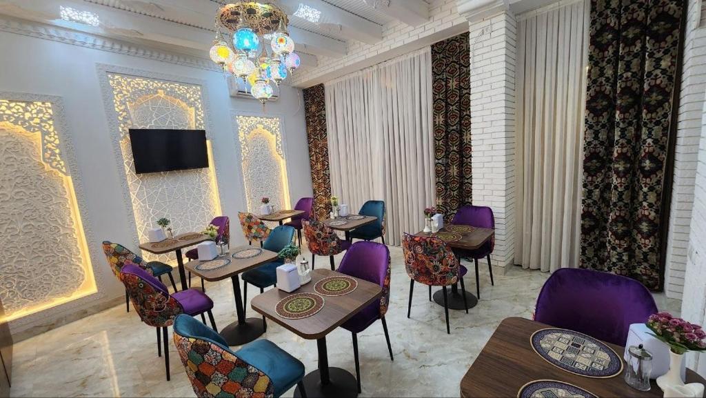 a restaurant with purple chairs and tables and a chandelier at GUZAL Hotel PREMIUM in Bukhara