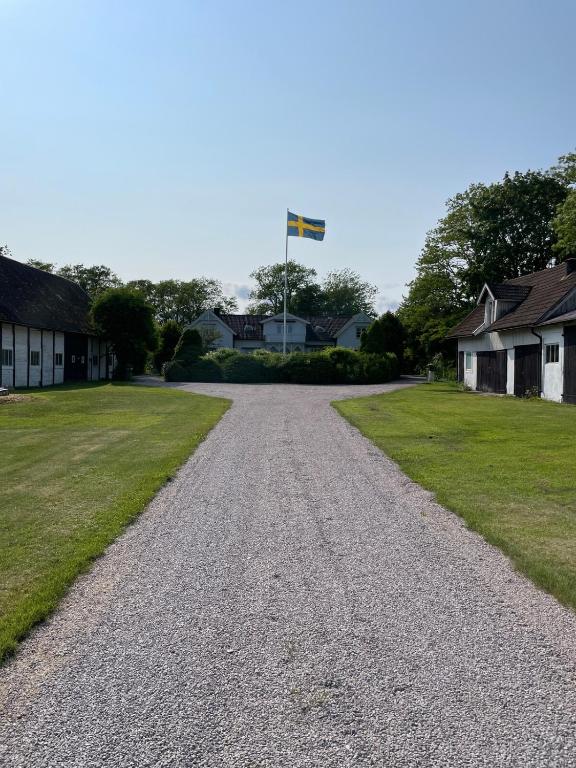 a gravel road with a flag pole in the distance at Thorsagården in Listerby