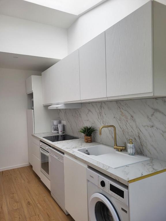 a white kitchen with a sink and a dishwasher at petite maison avec jardin in Berck-sur-Mer