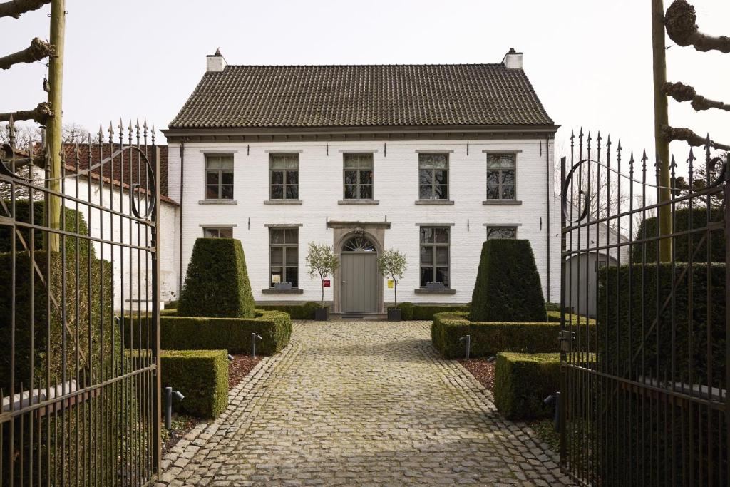 a white house with a gate in front of it at B&B Alexandre in Herzele
