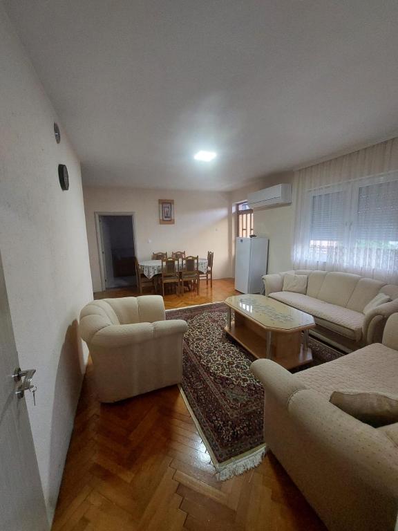 a living room with white couches and a table at Ariana Guest House in Prizren