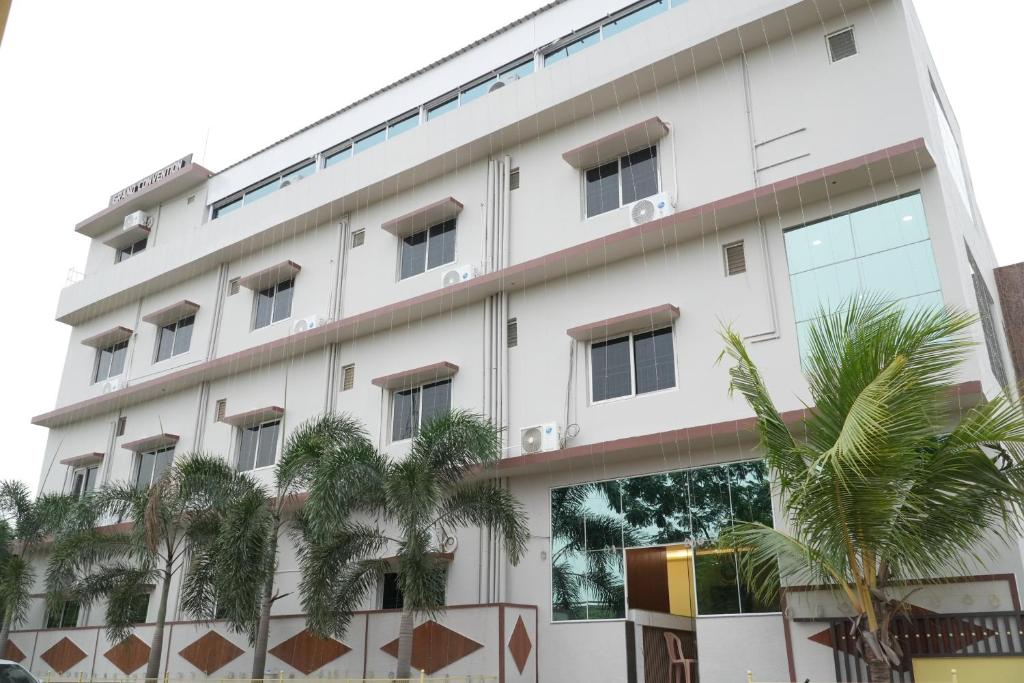 a white building with palm trees in front of it at Sri Laxmi Grand Convention in Tuni