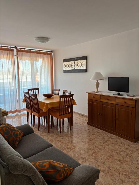 a living room with a table and chairs and a television at Apartamento vacacional Jávea in Jávea