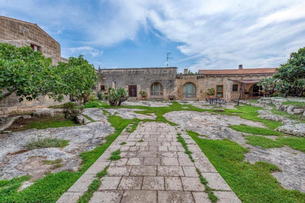 an old stone building with a stone pathway in a yard at Masseria Copertini in Vernole