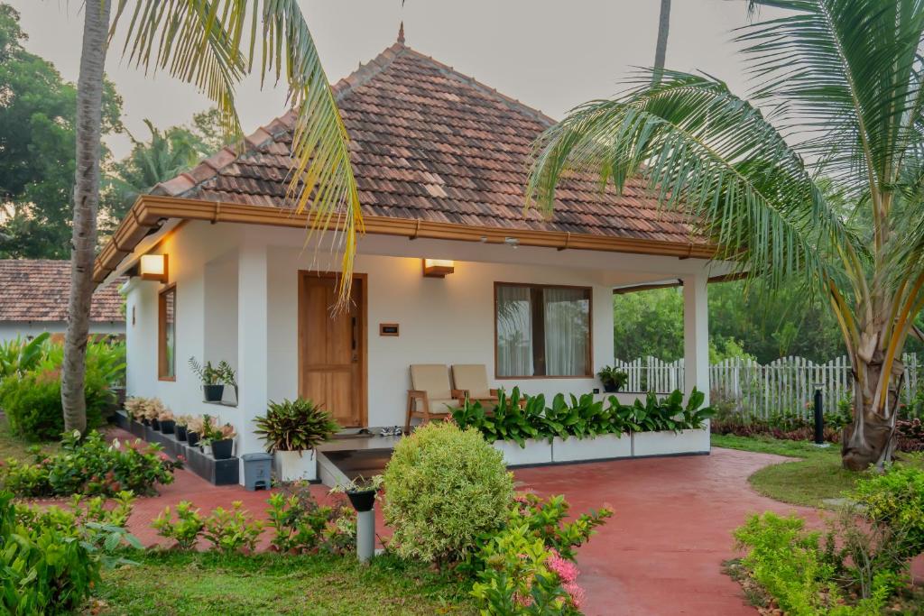 a house with a palm tree in front of it at Kaayal Luxury Villa Varkala Private Lakefront Retreat in Varkala