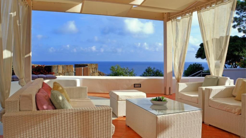 a living room with white furniture and a view of the ocean at Dammuso Vento Del Sud in Pantelleria