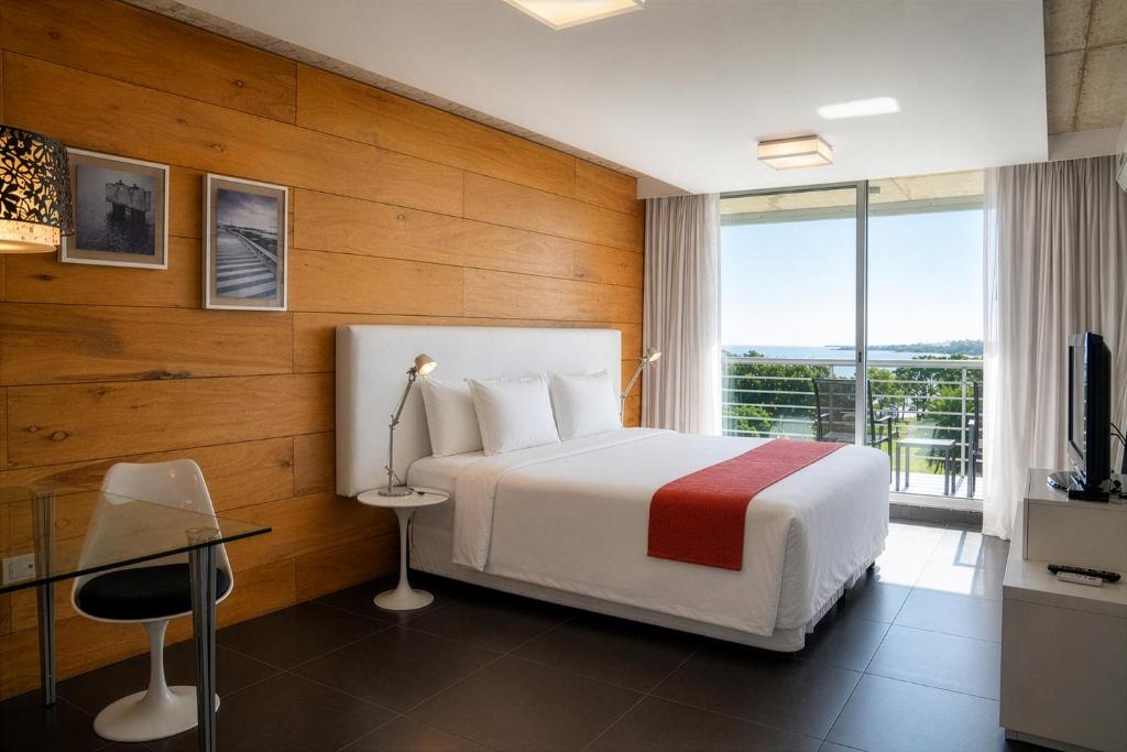 a hotel room with a bed and a large window at Costa Colonia - Riverside Boutique Hotel in Colonia del Sacramento