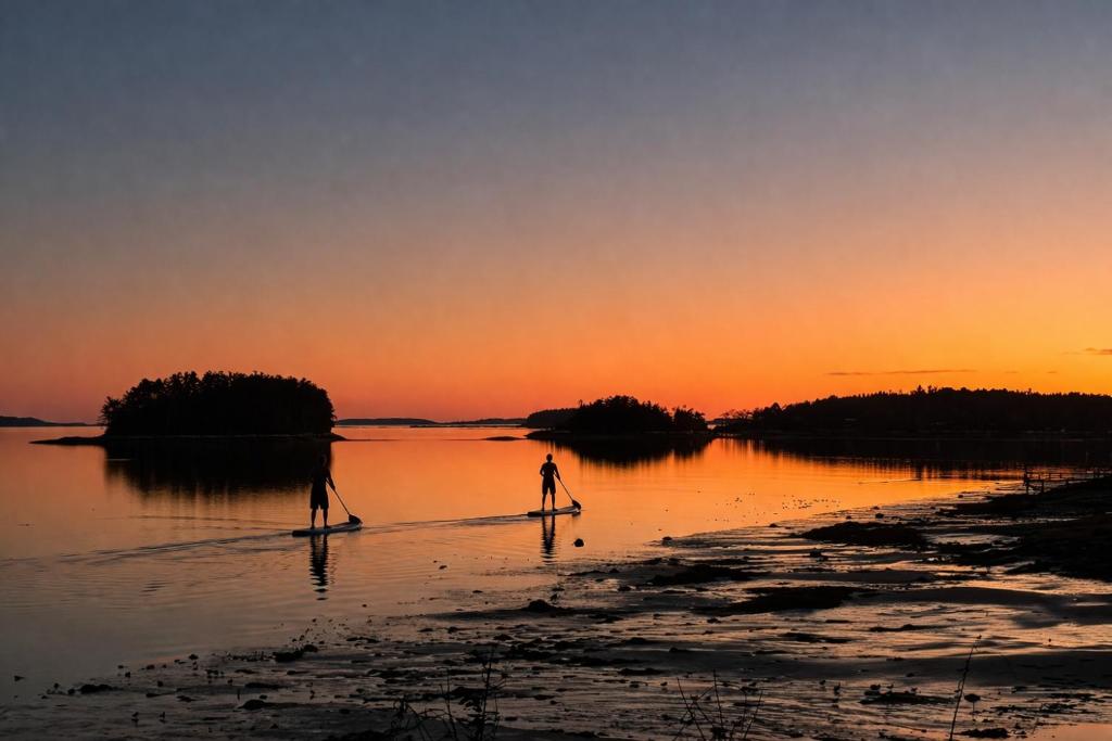 two people are paddle boarding in the water at sunset at Modern Ocean Front Home 4 bed, 5 bath Freeport in Freeport