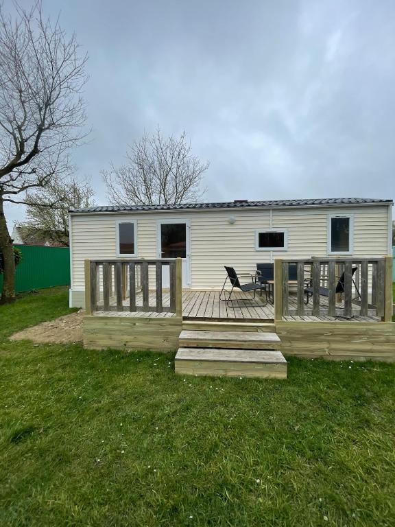 a house with a deck with a table and a bench at Bungalow Neila in Bourbourg